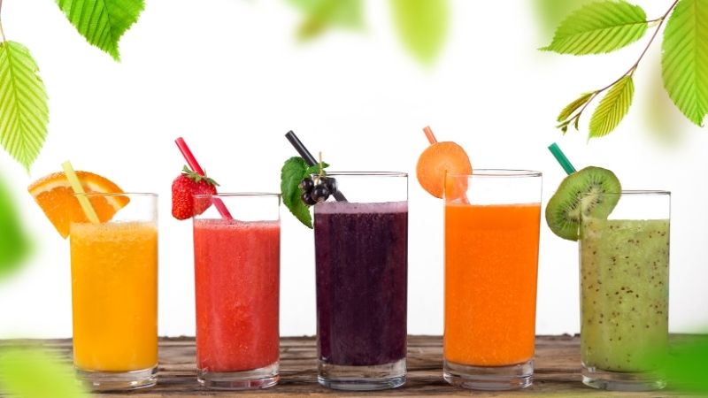 5 gläser mit bunten vitaminsäften stehen auf einer tischunterlage